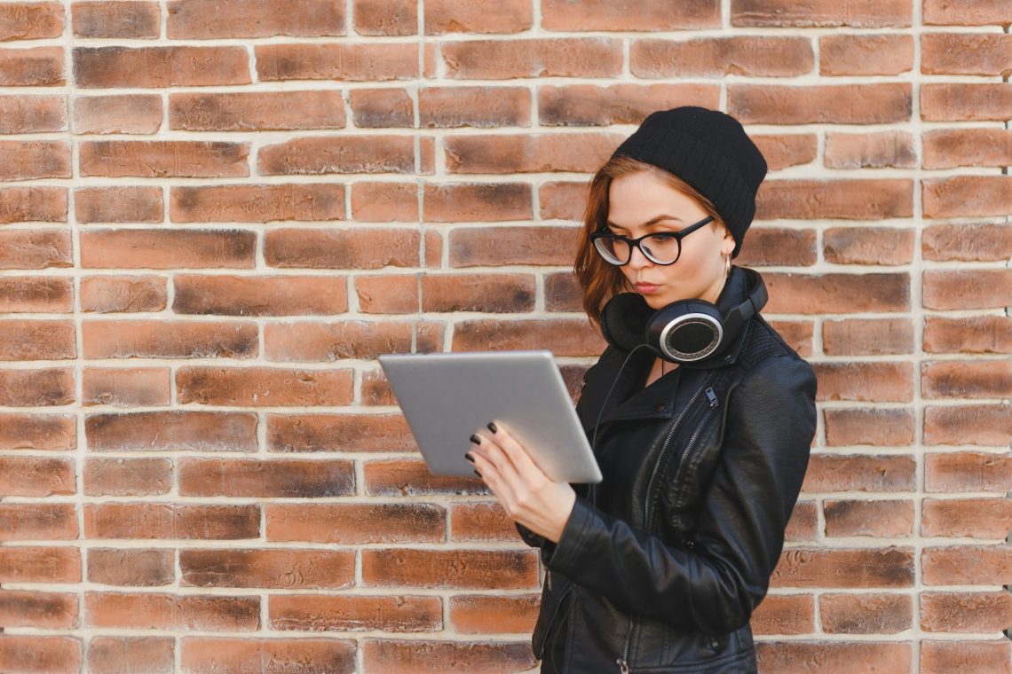 Happy beautiful woman using electronic device, looking at screen. Copy space