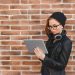 Happy beautiful woman using electronic device, looking at screen. Copy space